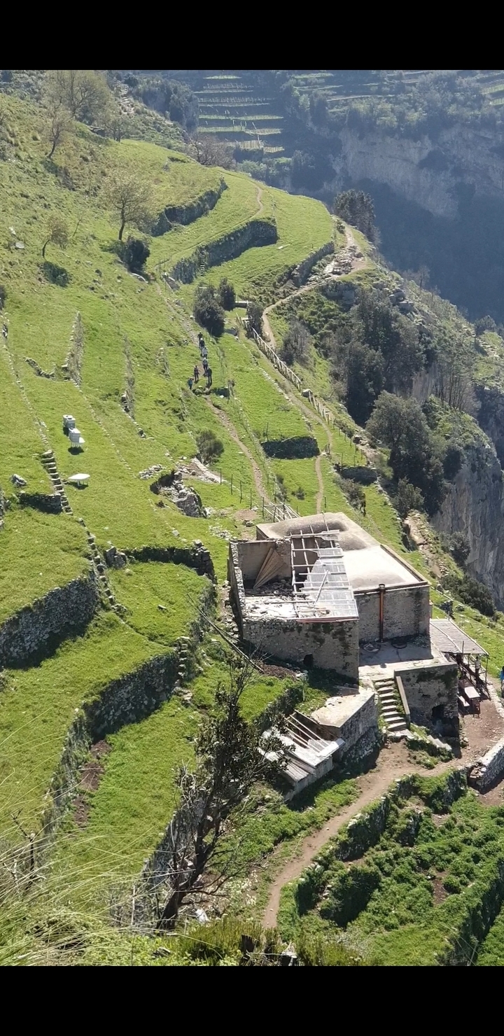 Un bâtiment abandonné sur un paysage herbeux avec des sentiers.