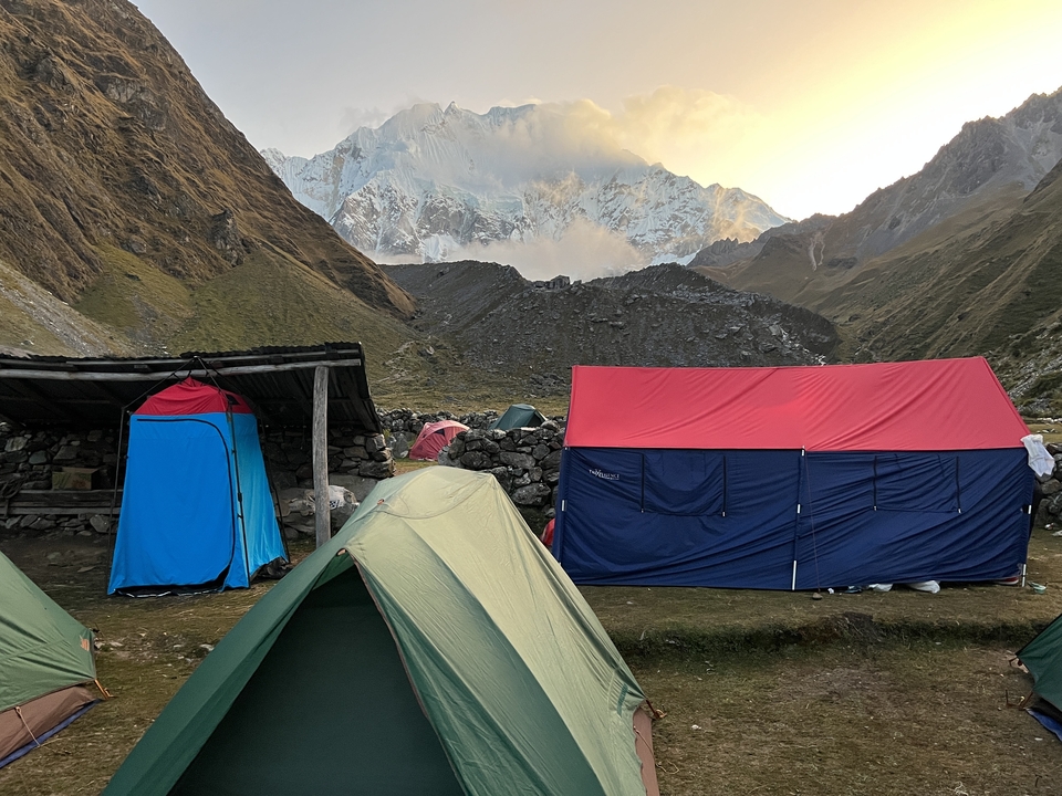 Camping site with colorful tents and a mountain backdrop.