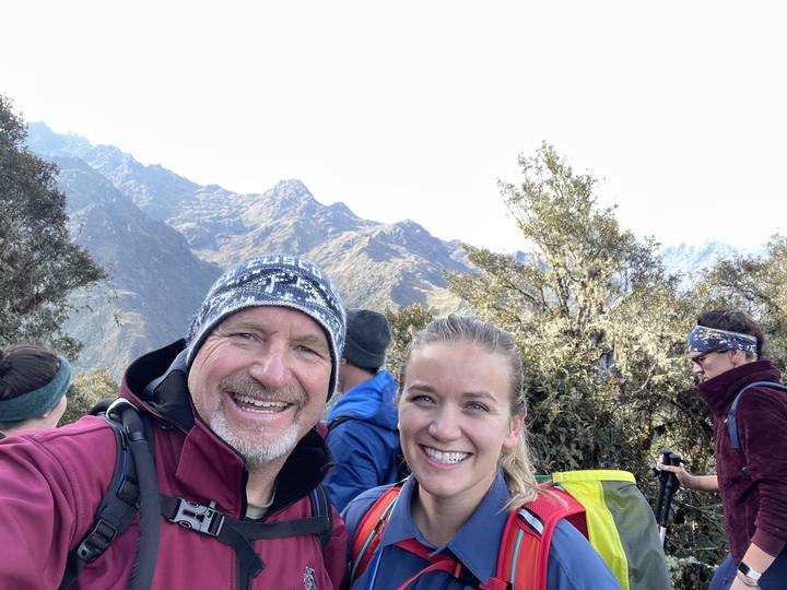 Two people smiling at the camera with a mountainous backdrop.