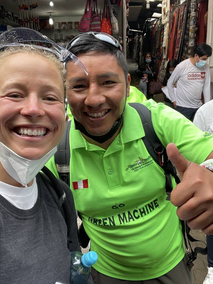 Two people posing in a bustling market.