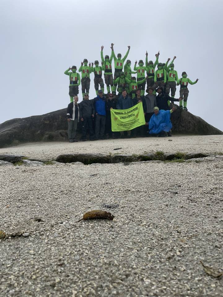 Group of hikers posing with a banner, partially obscured.