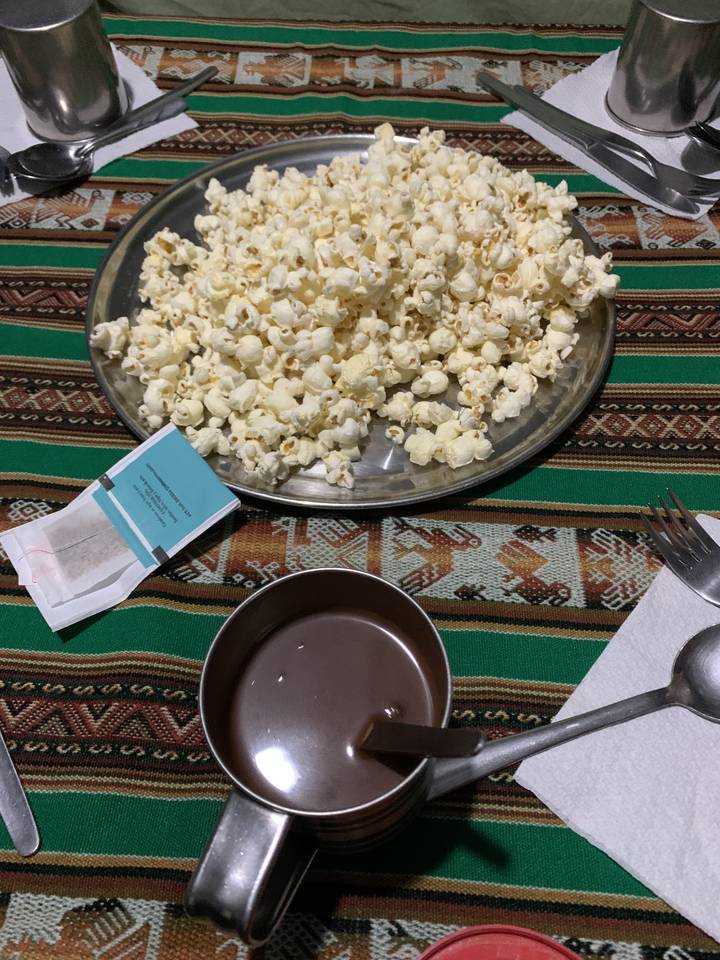 Popcorn and a beverage on a patterned table cloth.
