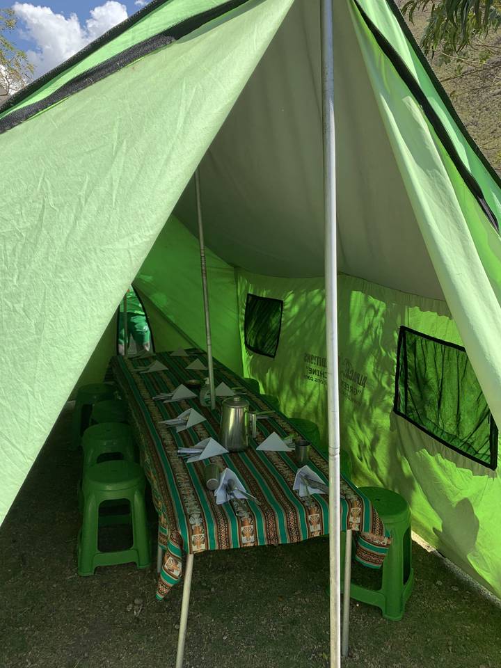 Dining tent with table and chairs setup for a meal.