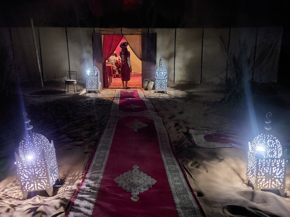 Evening view of a person in a desert camp with lanterns.