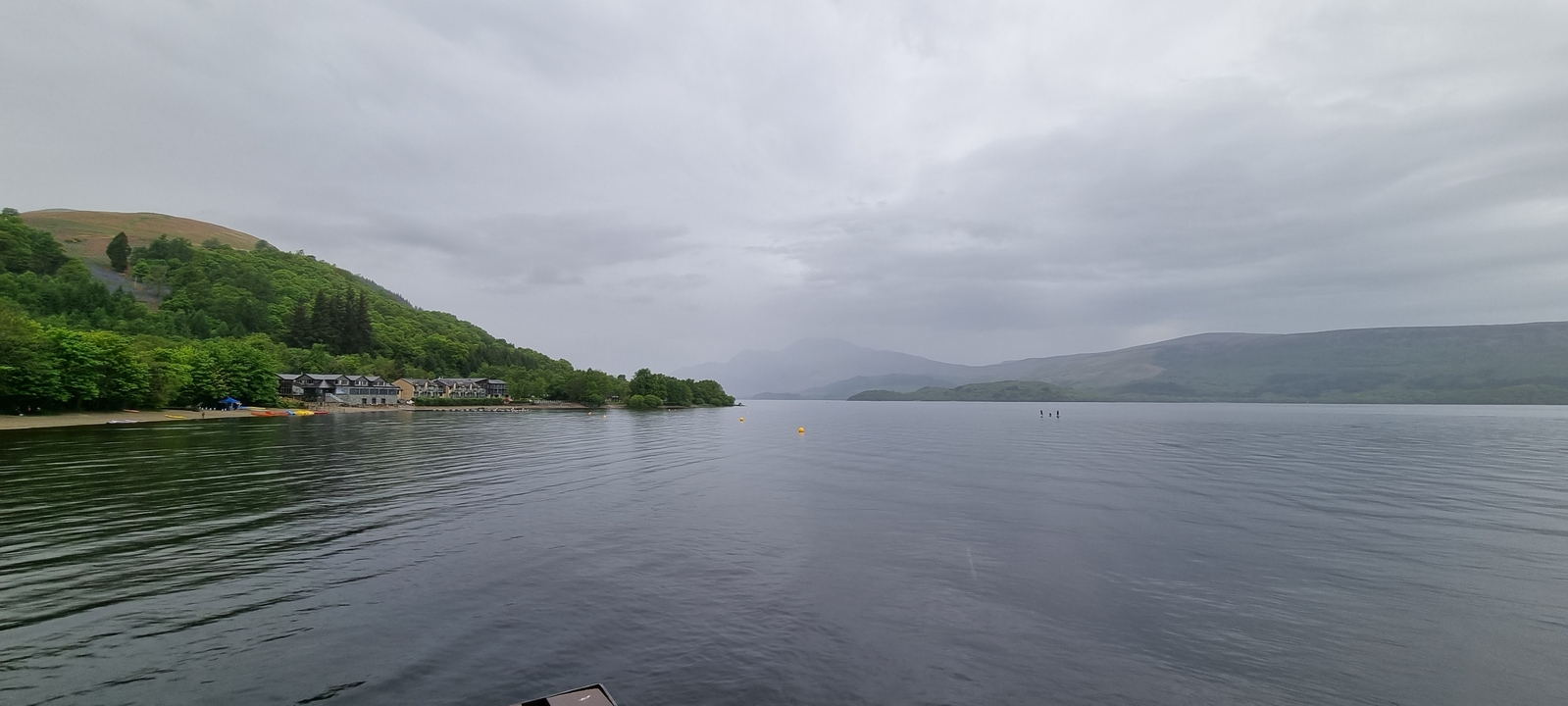 Distant view of loch with buildings and hills.