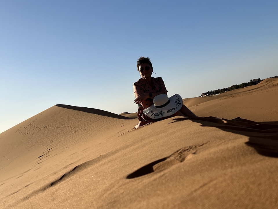 Une personne portant un chapeau assise dans un paysage désertique.