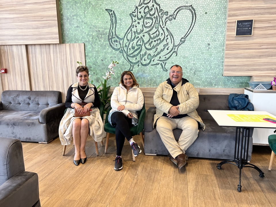 Trois personnes assises à l'intérieur, souriantes.