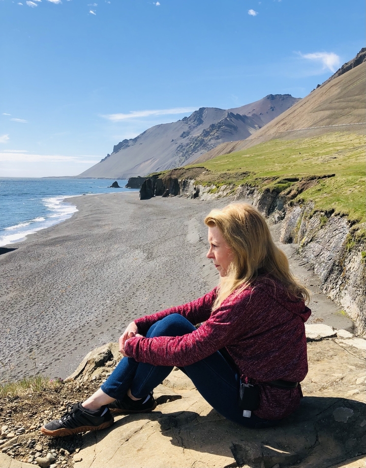 Person sitting and gazing at a coastal view.