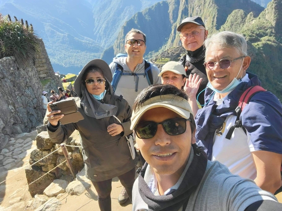 Happy group of tourists posing in front of Machu Picchu ruins.