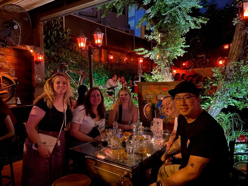 Group of people sitting together in a garden cafe setting at night.