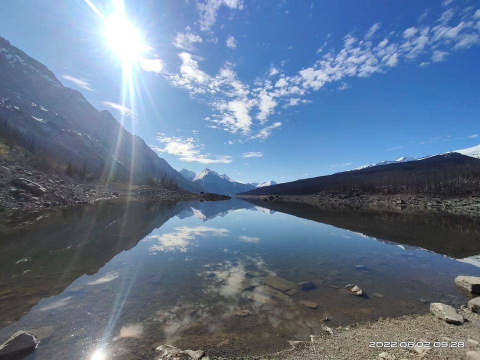 Un lac calme reflétant les montagnes et un ciel dégagé.