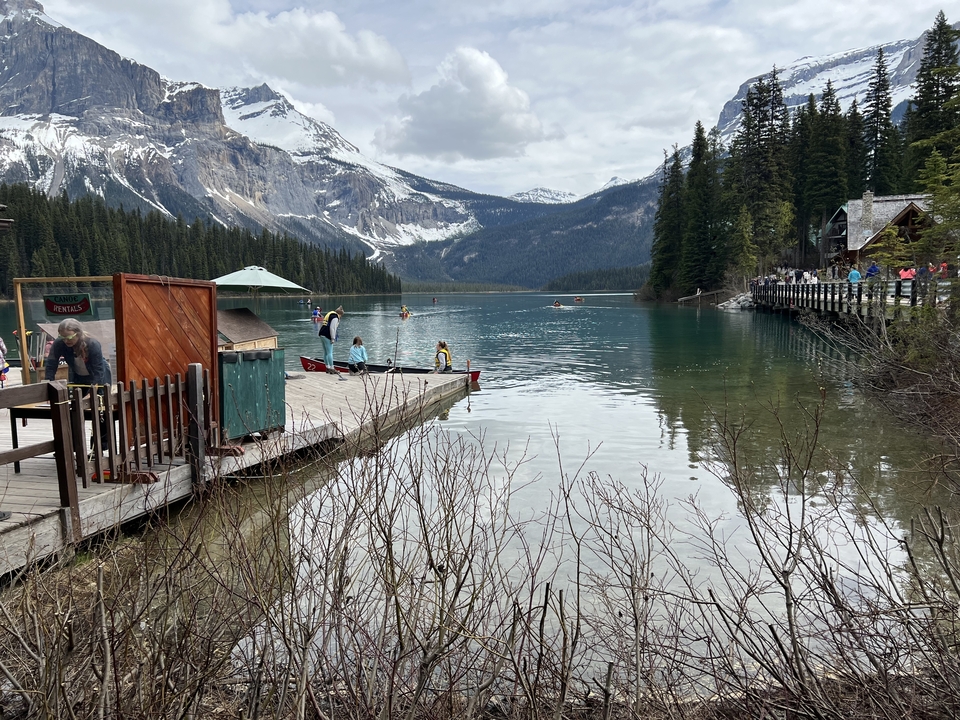 Des personnes font du canoë sur un lac avec des montagnes en arrière-plan.