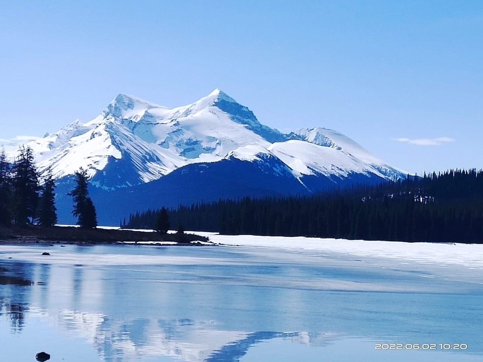 Des montagnes enneigées se reflètent dans un lac.