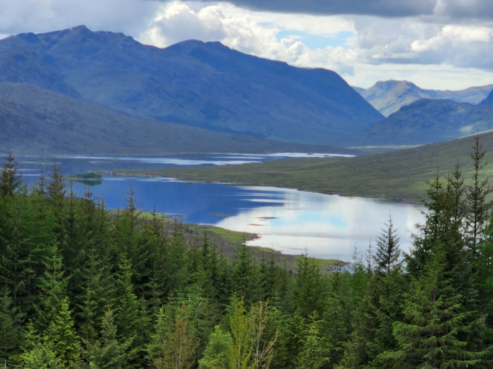 A scenic lake view surrounded by hills and forests.