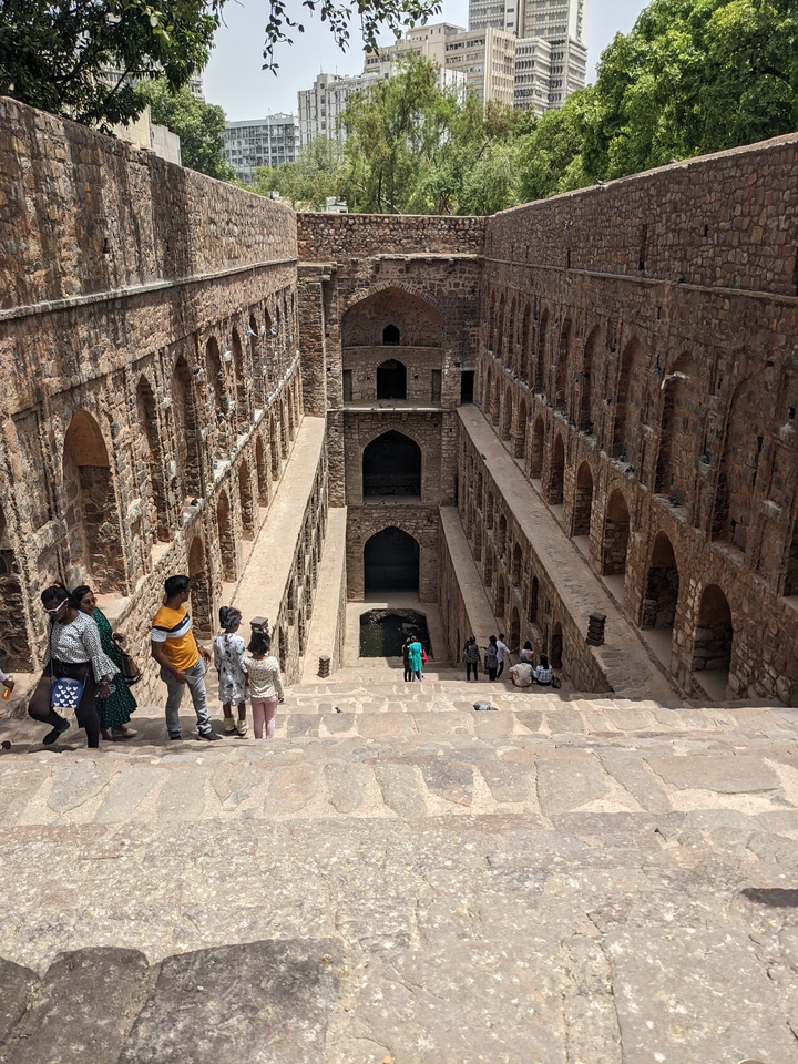 Tourists exploring an ancient stepwell with high walls.