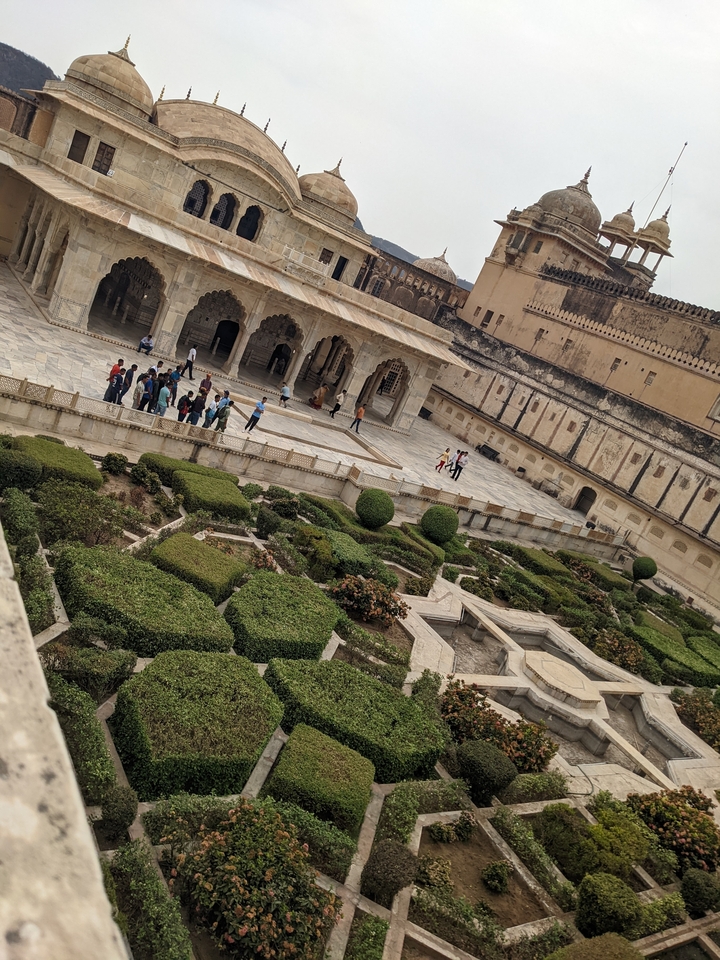 Tourists walking in a courtyard with manicured gardens.