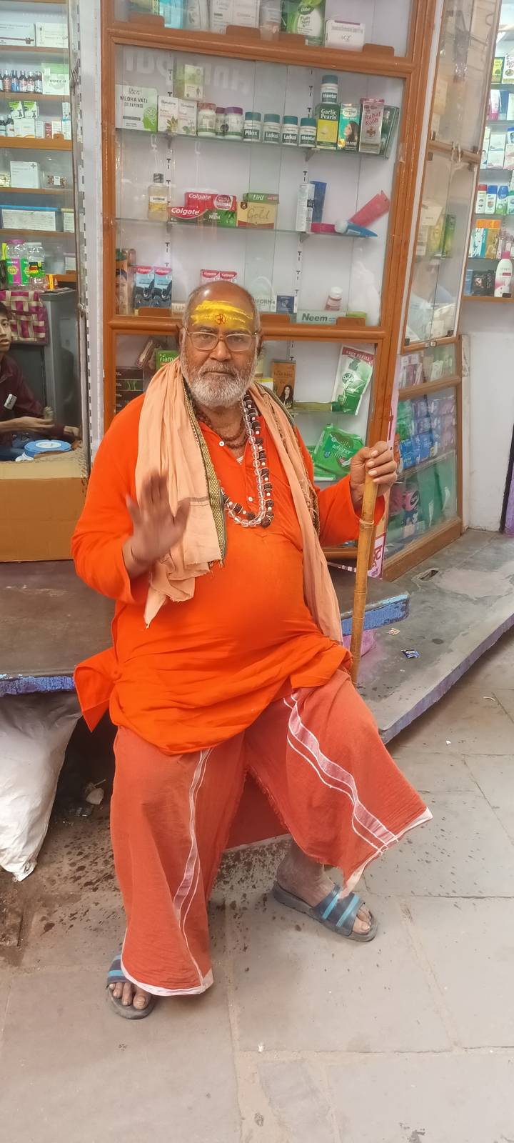 Homme en tenue traditionnelle orange tenant un bâton.