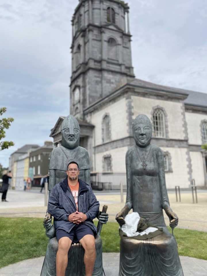 Person standing in front of sculptures and a historic building.