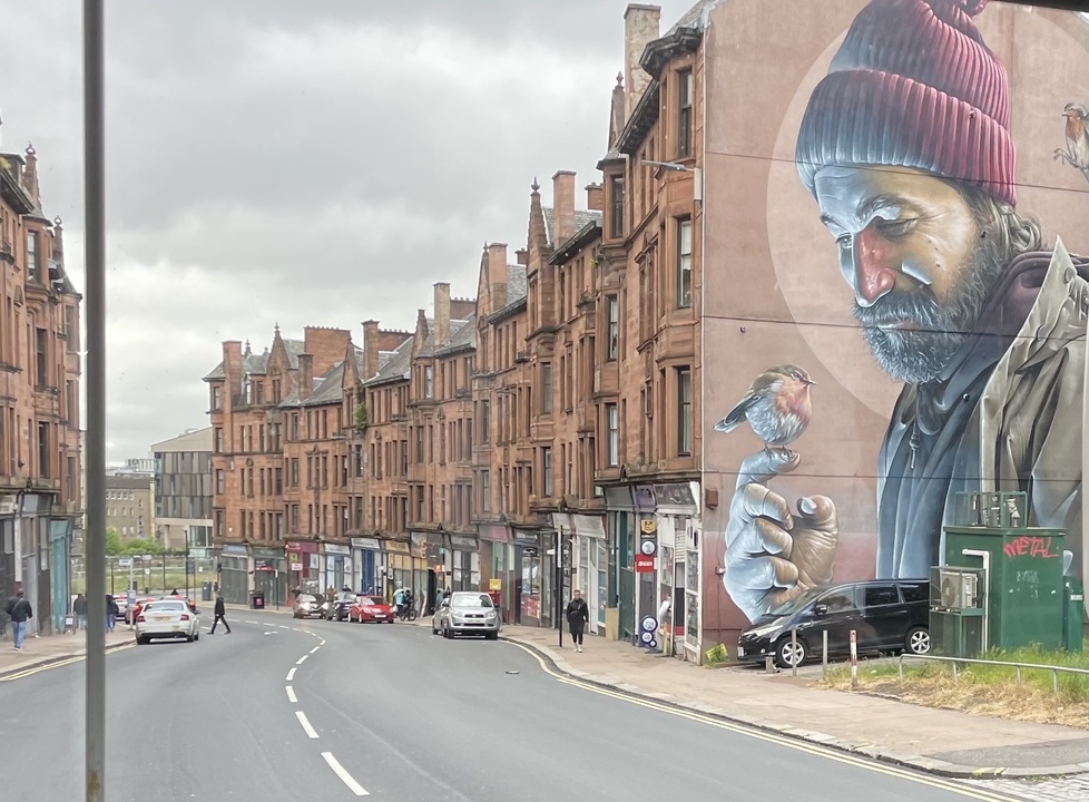 Street scene with buildings and a large mural of a man with a bird.