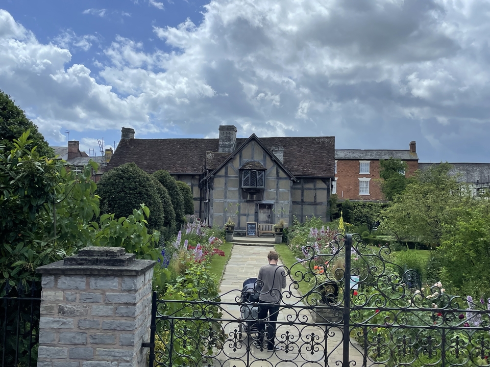 A person walking towards a traditional half-timbered house.