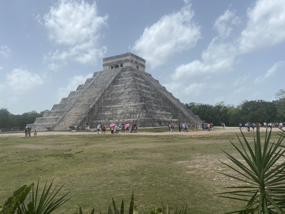 A large step pyramid with tourists at its base.
