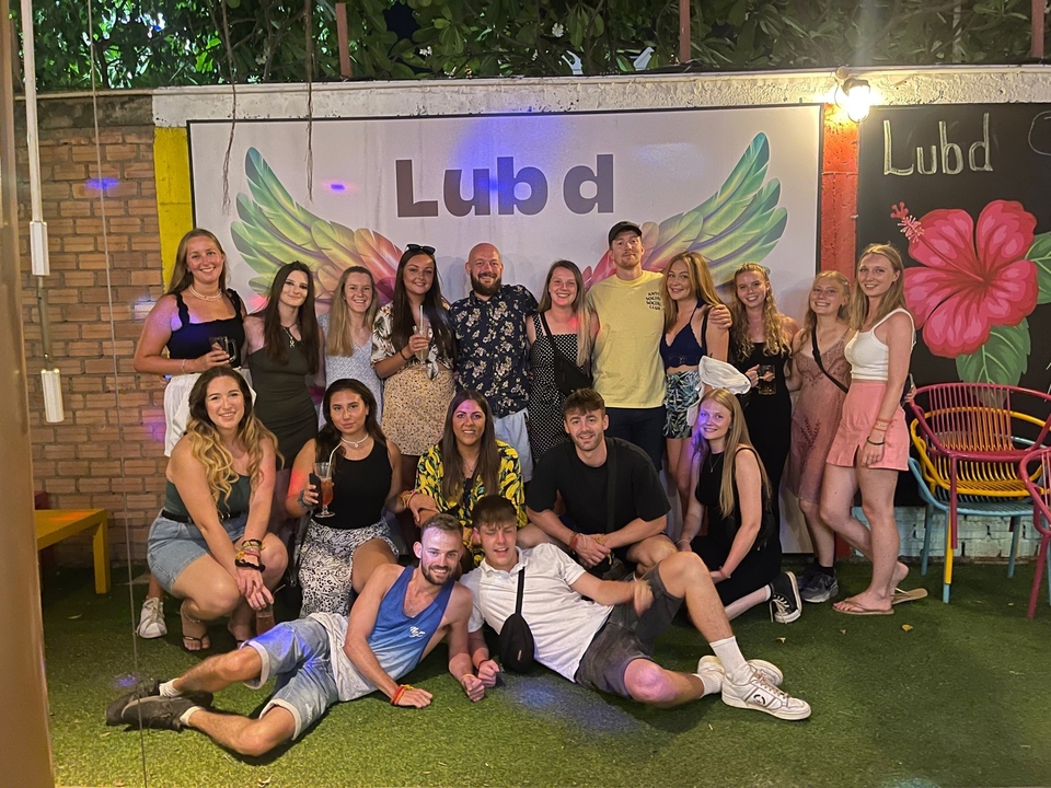 A group of young people posing in front of a mural with wings.