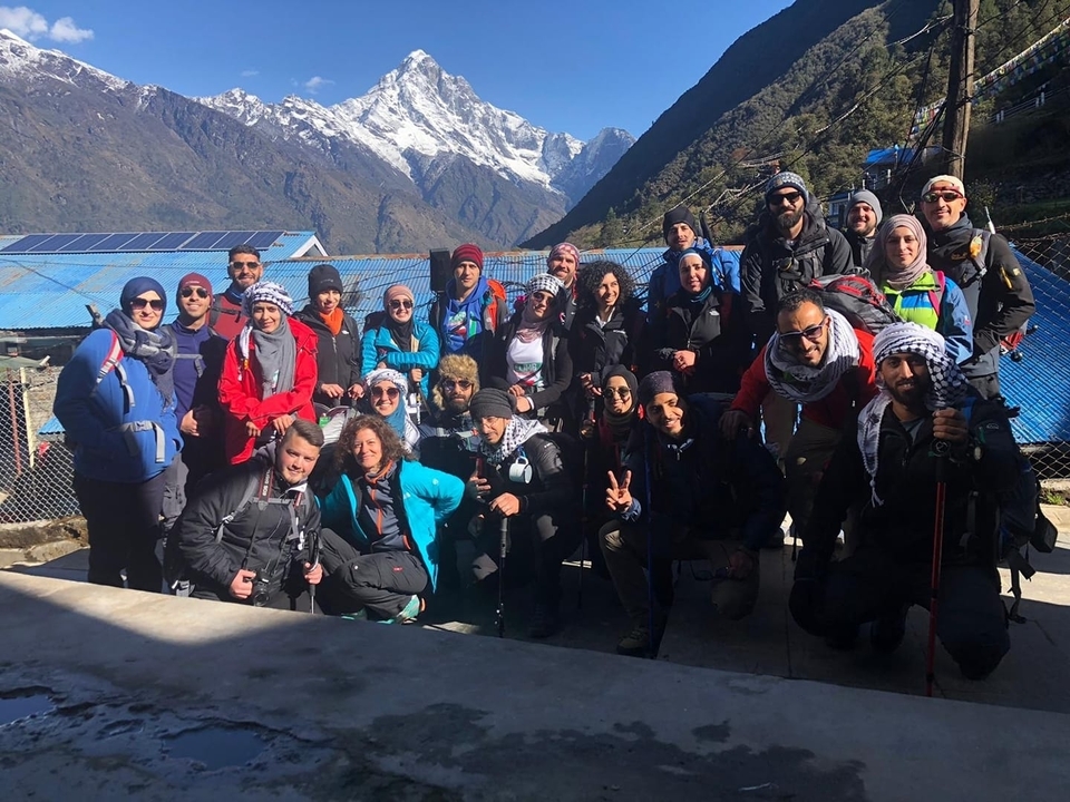 Un groupe de randonneurs posant avec des montagnes enneigées en arrière-plan.