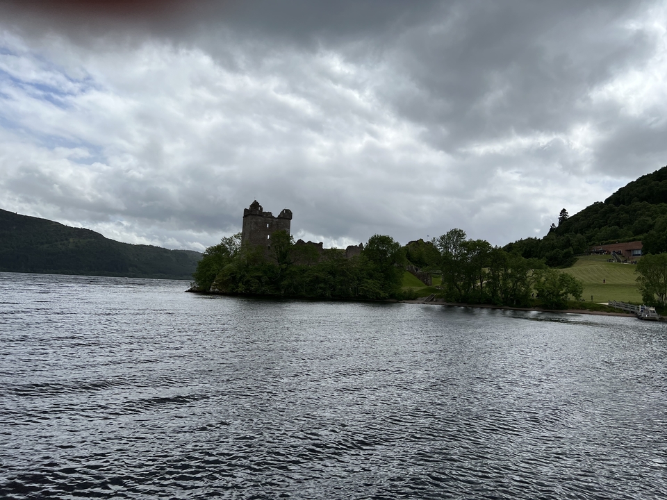 A historic castle by a lake surrounded by lush greenery.