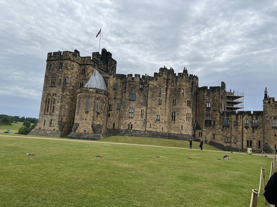 A large stone castle situated on a grassy area under a cloudy sky.