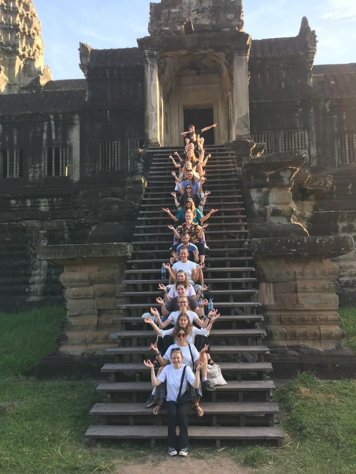 People posing on the steps of a historic site.