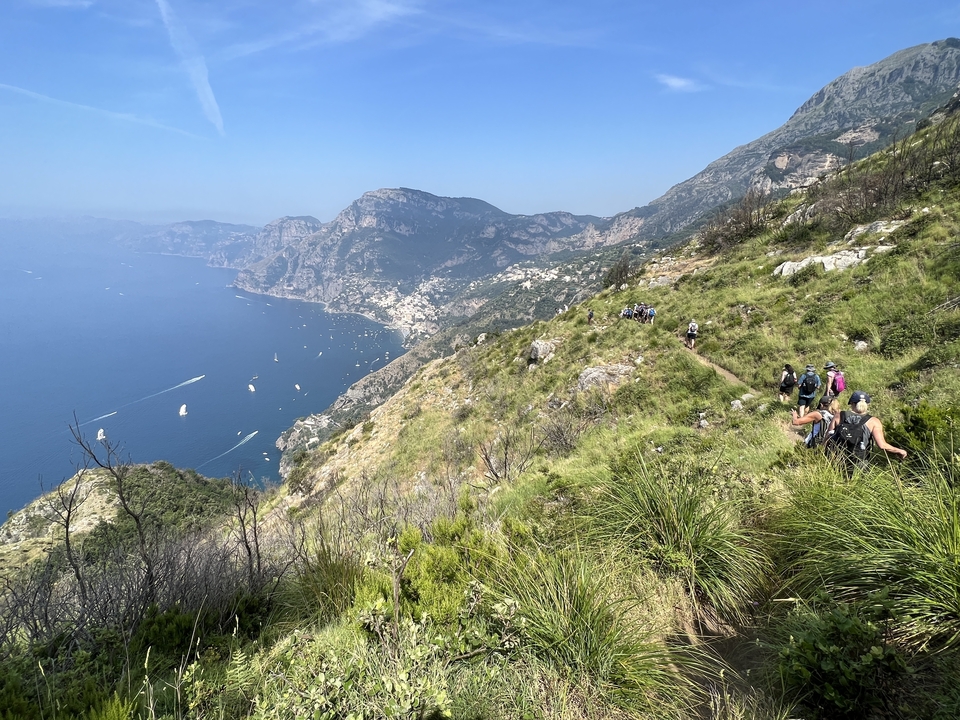 Hikers on a trail overlooking a scenic coastal landscape.