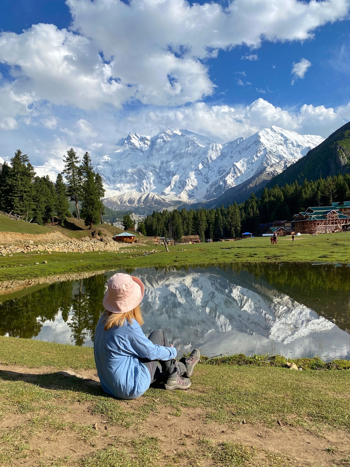 A scenic view of a mountain reflecting in a pond with wooden lodges.
