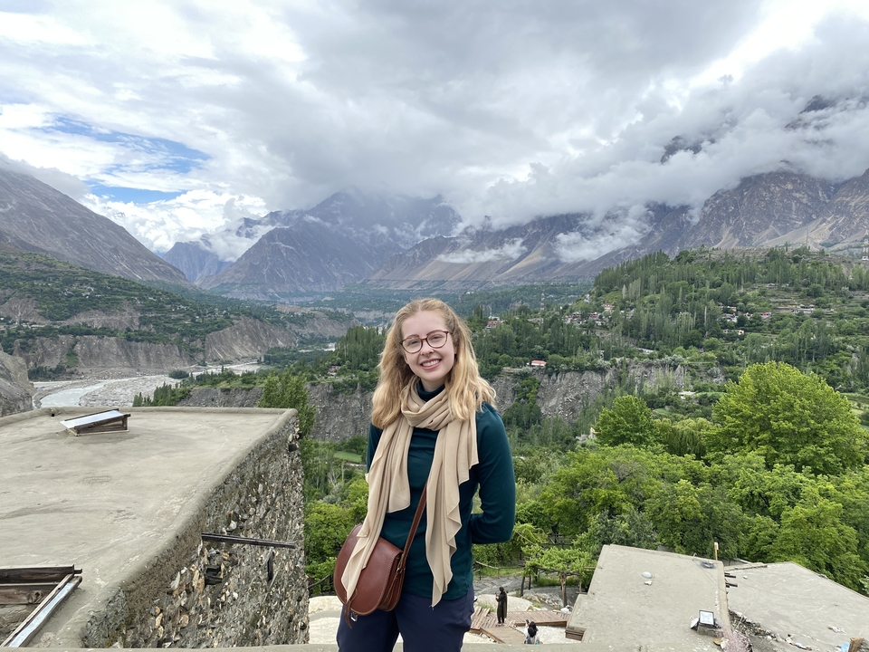 A person smiling with a mountainous landscape behind.