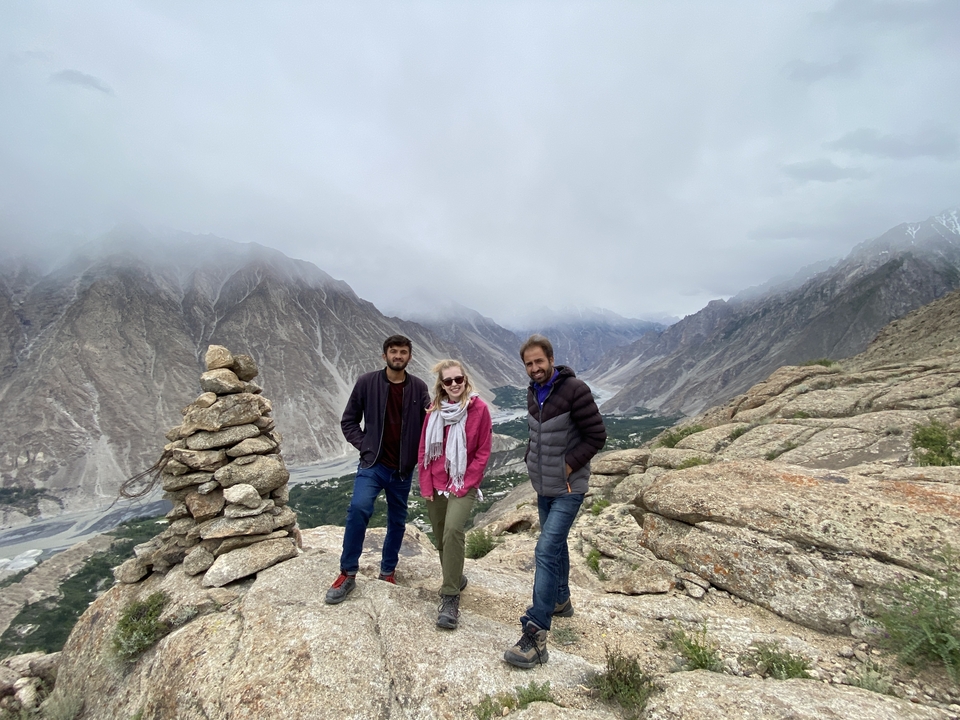 Three people standing on a rocky mountain path with a scenic view.