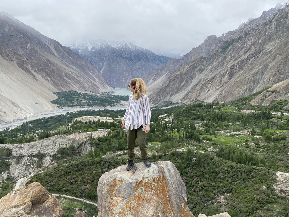 A person standing on a rock with a vast mountain landscape.