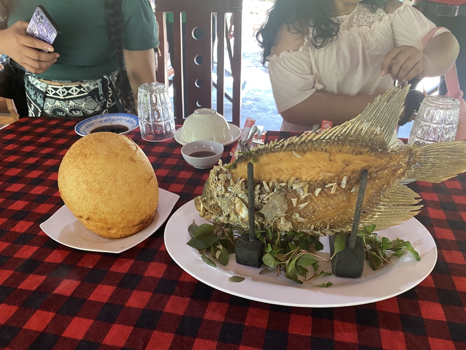 A table with a fried fish and a large pastry served on plates.