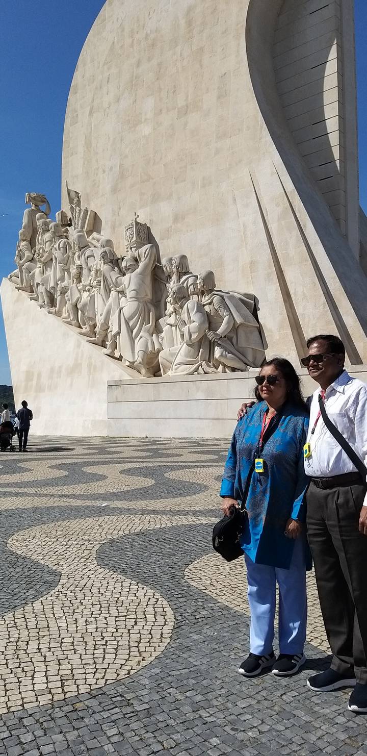 Des gens debout près d'un monument avec des sculptures détaillées.
