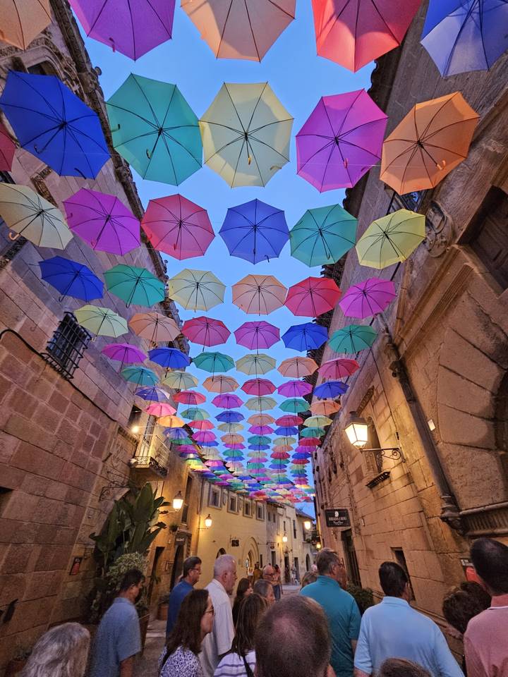 Parapluies colorés suspendus au-dessus d'une rue étroite.
