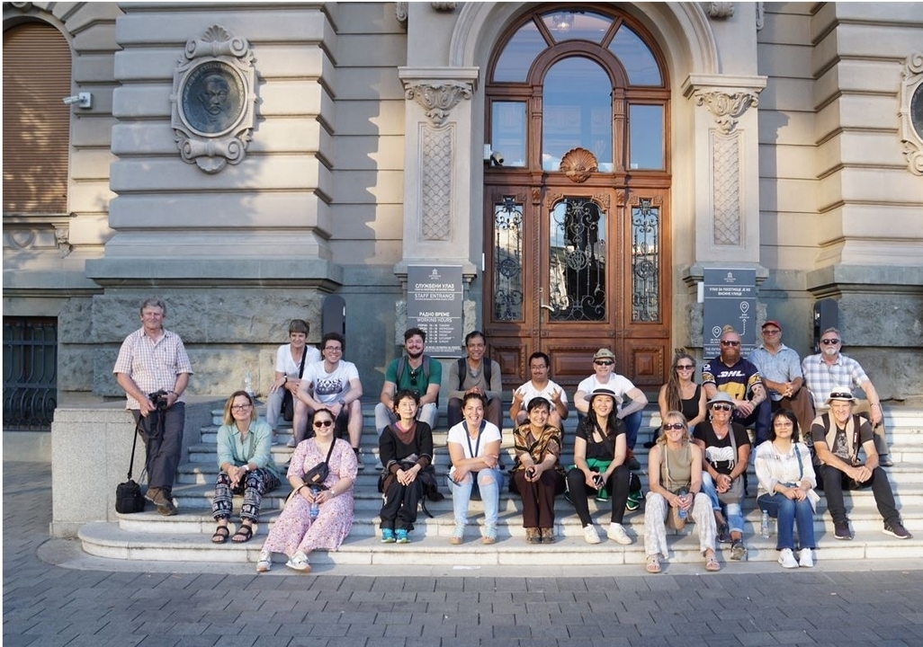 Groupe de personnes posant sur les marches devant un bâtiment historique.