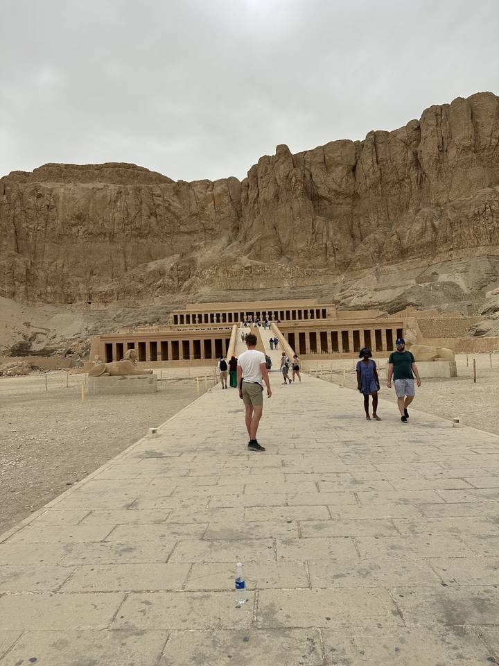 Touristes marchant vers des ruines de temple antique.