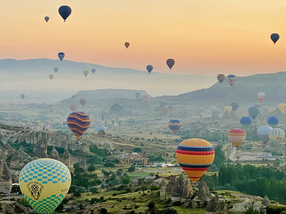 Des montgolfières s'élèvent au-dessus du paysage à l'aube.