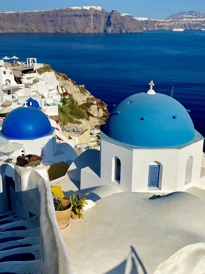 Dômes bleus emblématiques et bâtiments blancs face à une mer limpide.