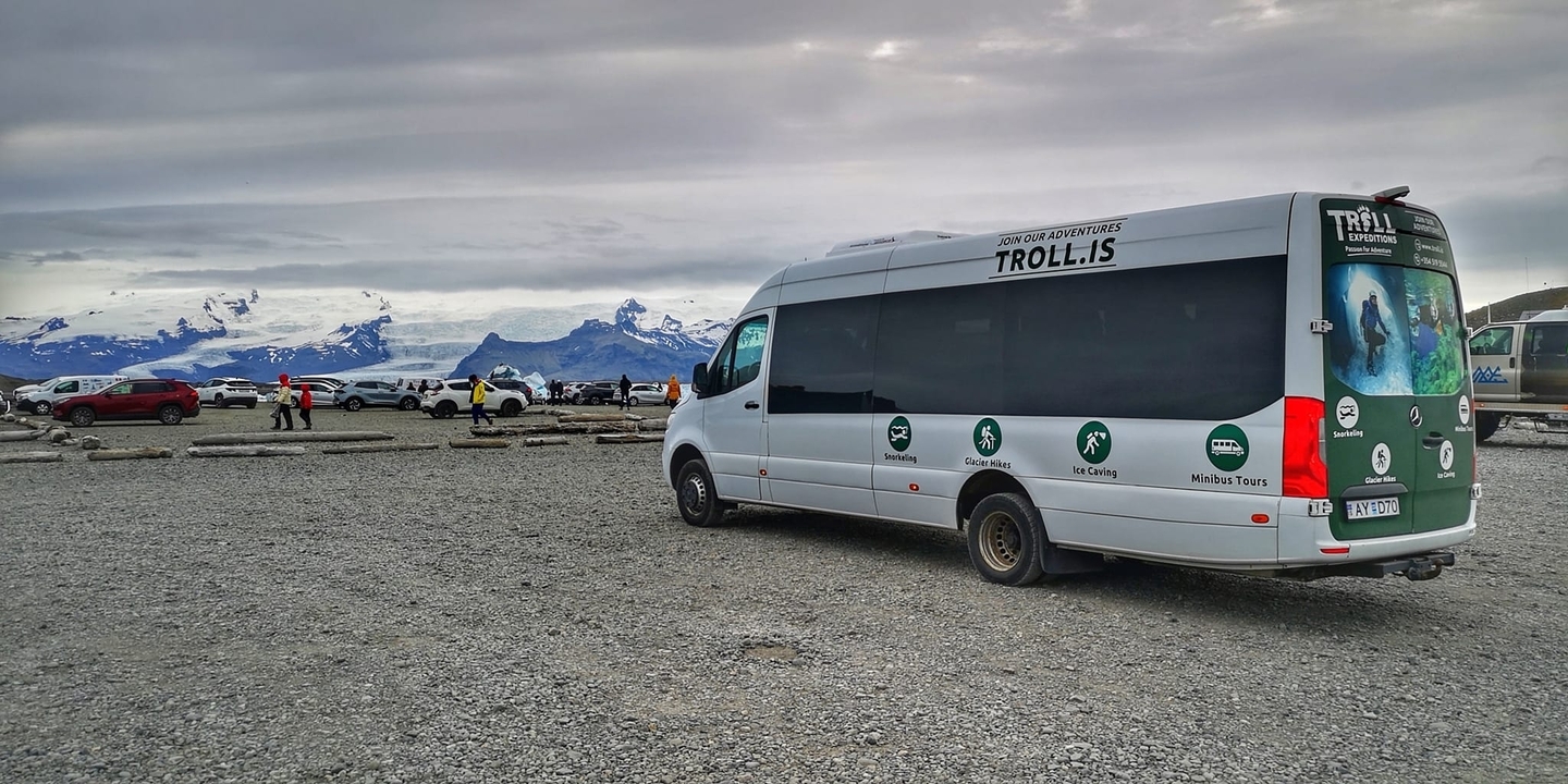 Autocar de tourisme avec des voitures garées et des montagnes enneigées