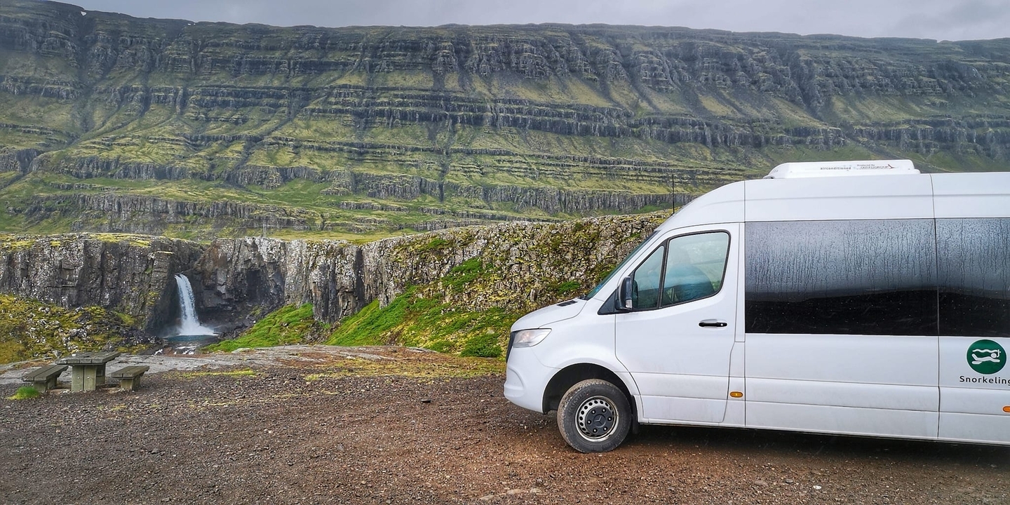 Autocar de tourisme près d'une cascade et d'un paysage de montagne
