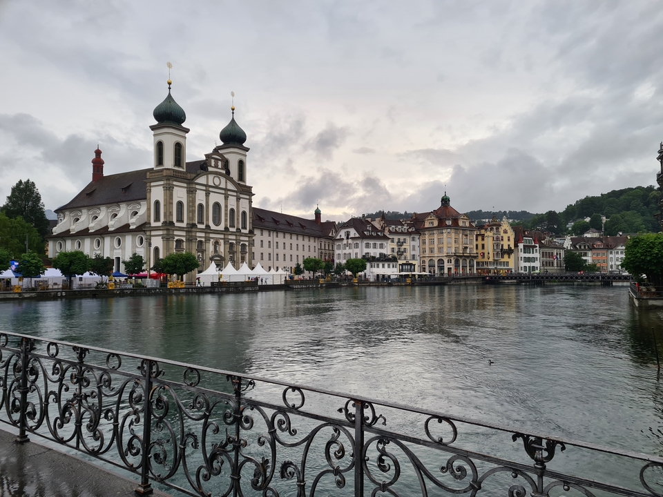 A scenic view of a baroque church along a river with picturesque buildings.