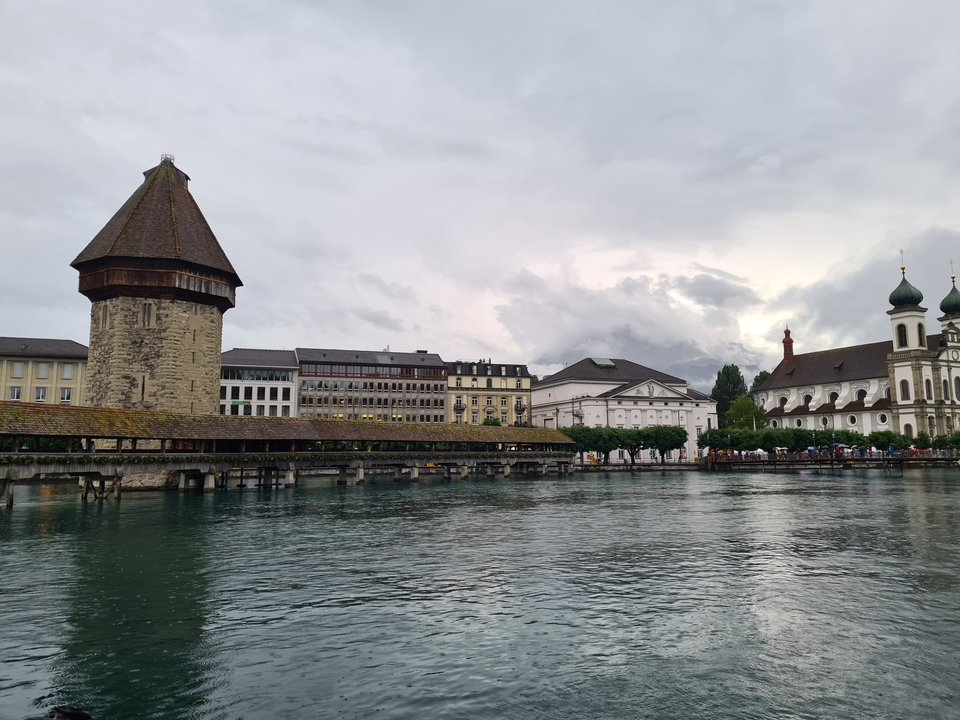A historic bridge and buildings along a river with mountains in the background.