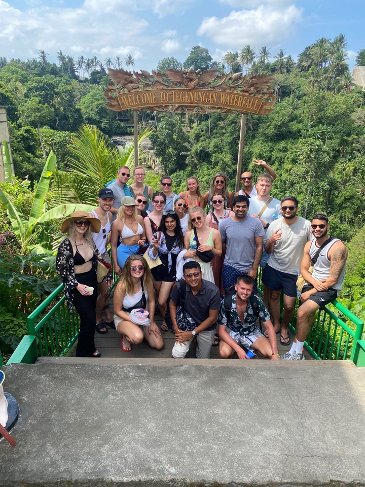 Group of tourists posing in front of lush greenery.