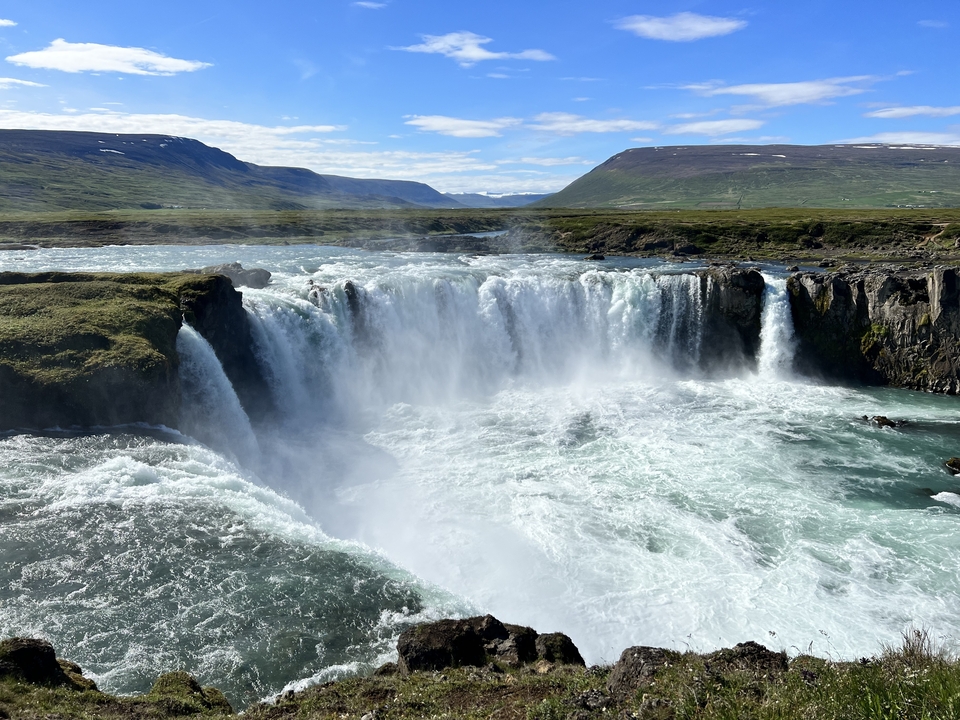 A wide waterfall under a clear blue sky.