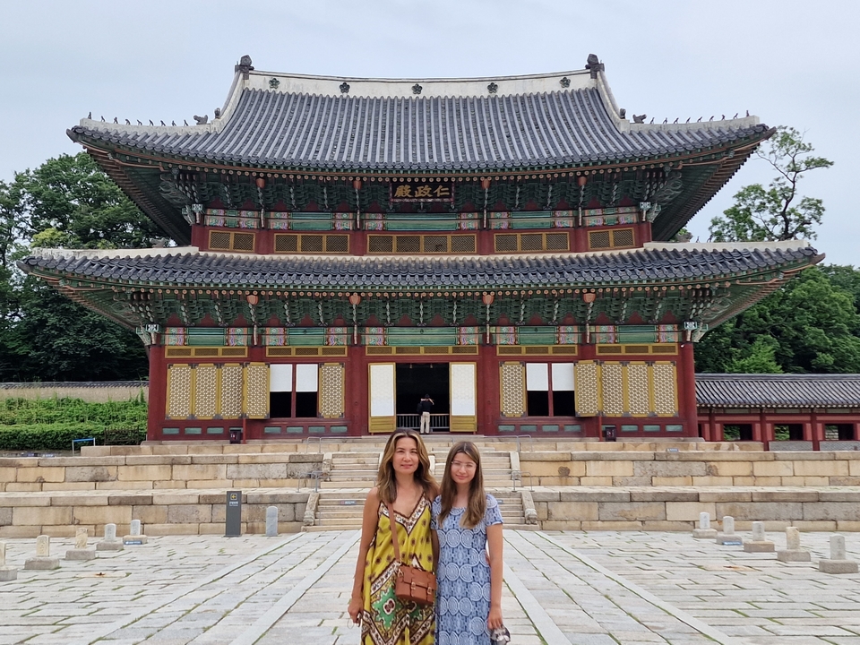 Two people standing in front of a traditional Korean building.