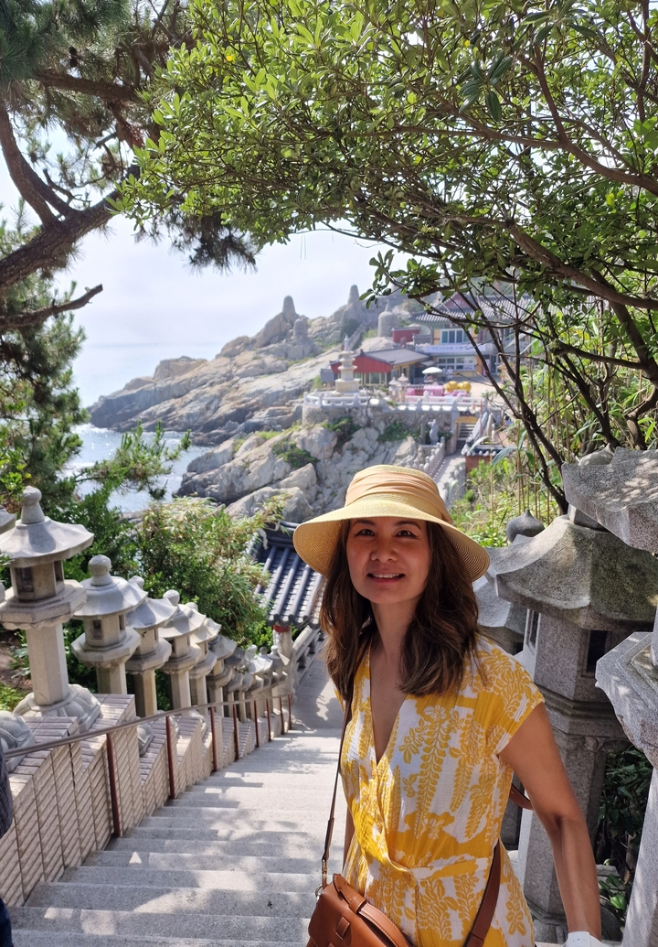 Woman posing with a coastal temple in the background.